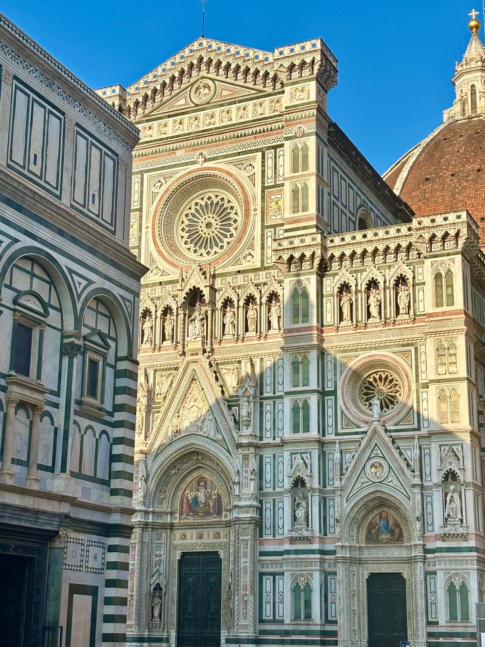 Florence Cathedral façade with ornate Gothic architecture, intricate details, and a large rose window under a clear sky