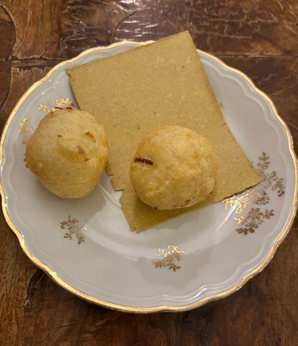 Two balls of bread and a rectangular flatbread on a decorative plate, set on a wooden table