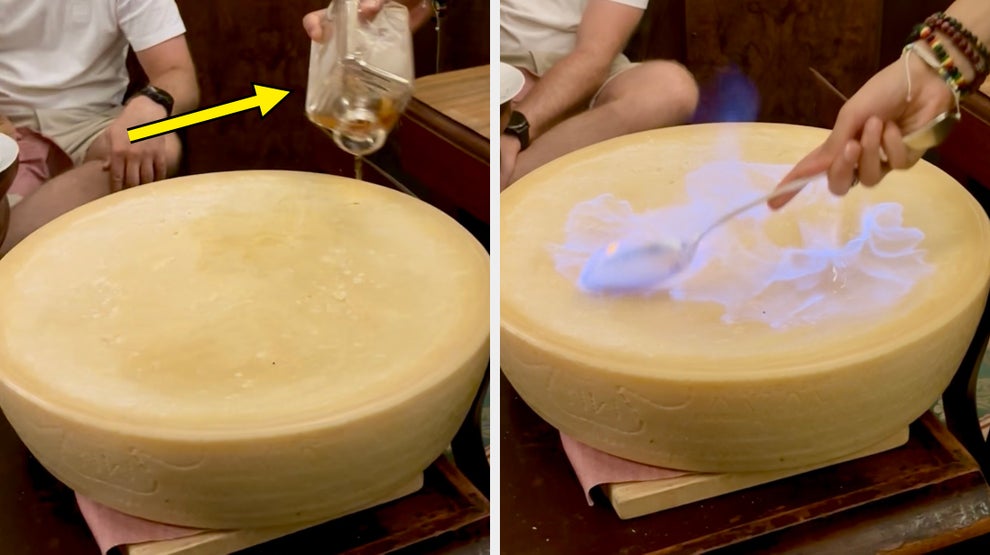 Cheese wheel being prepared with flaming technique at a restaurant, showcasing a unique culinary presentation
