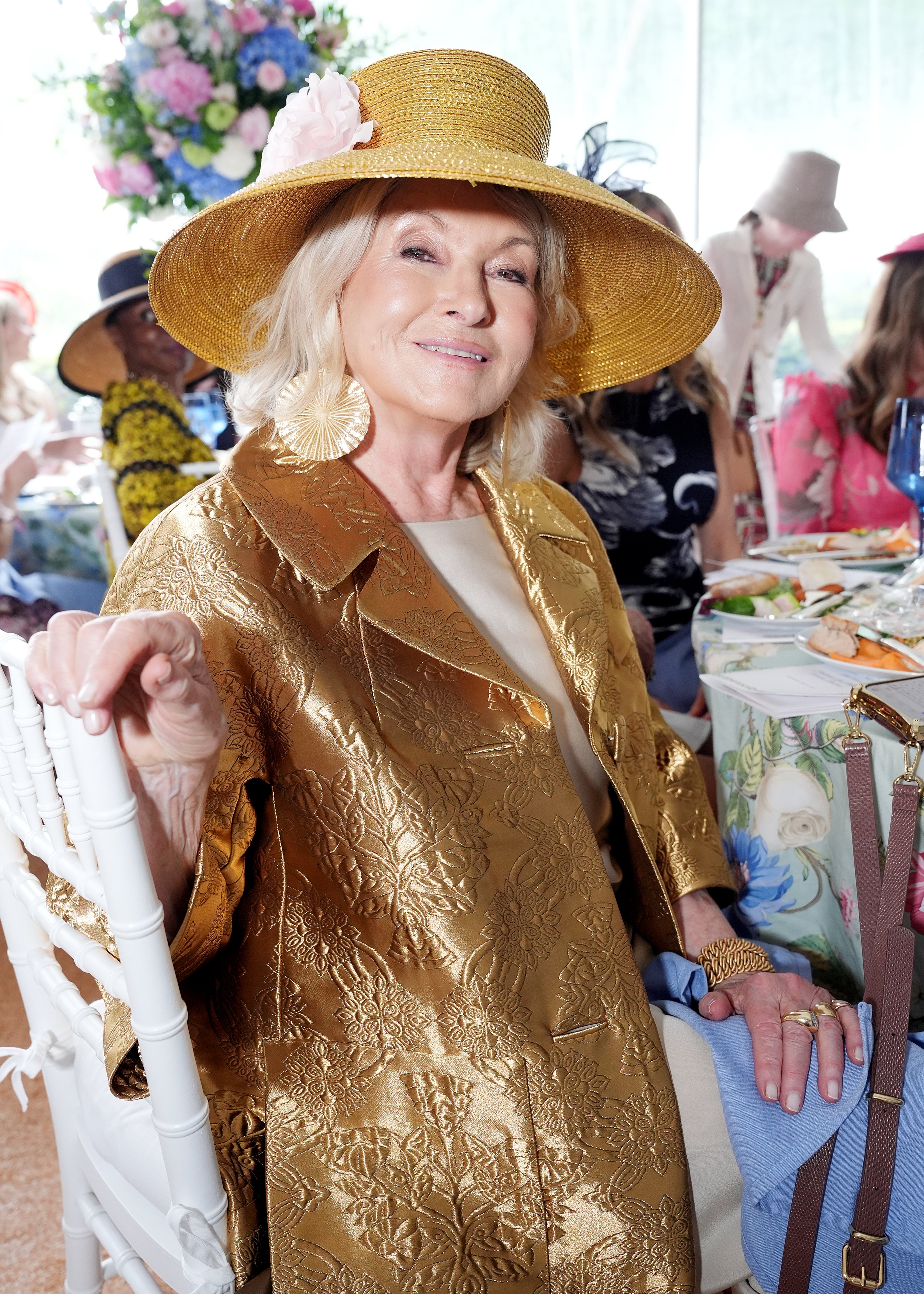 Martha Stewart at an event in a gold suit jacket and straw hat