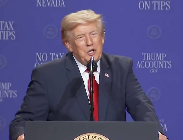 A person in a suit speaks at a podium with a seal, against a backdrop with "NO TAX ON TIPS" and "TRUMP ACCOUNTS" text