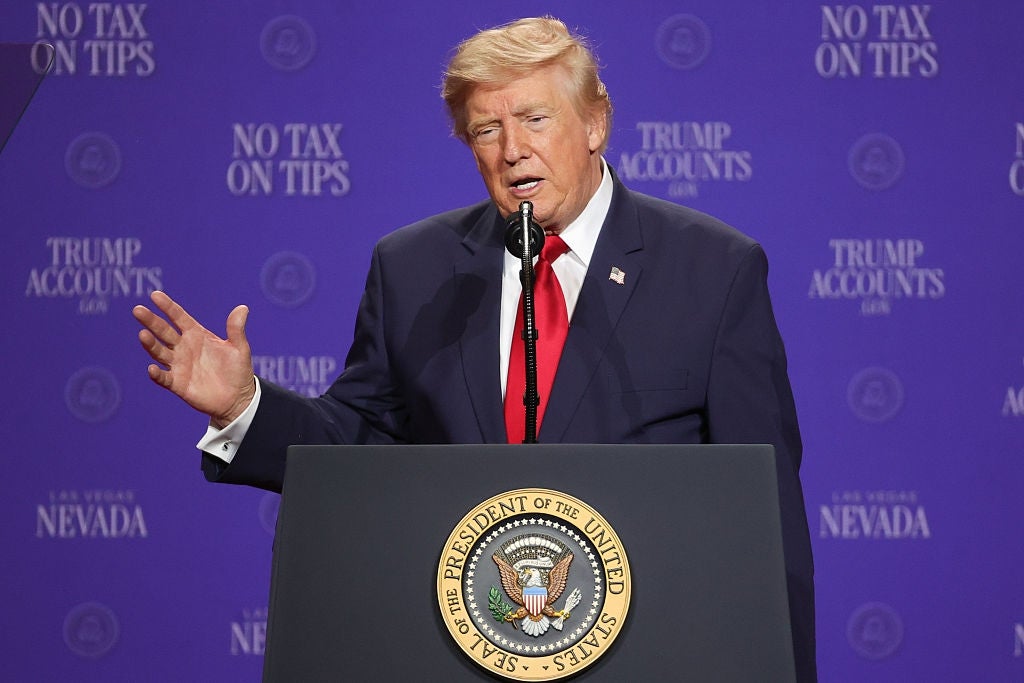 En person i dress snakker ved et podium med «Ingen skatt på tips»; og "Trump-kontoer" i bakgrunnen