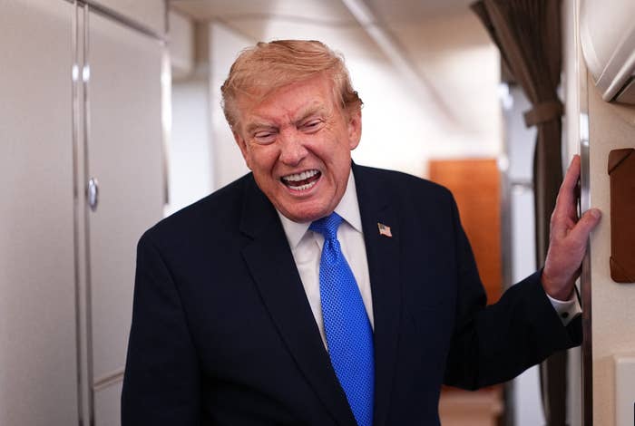 A person in a suit and tie is laughing inside an aircraft cabin