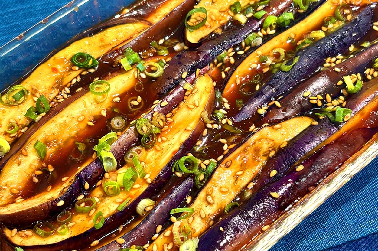 ガラス皿に入ったナス料理。上にはネギとゴマがトッピングされている。