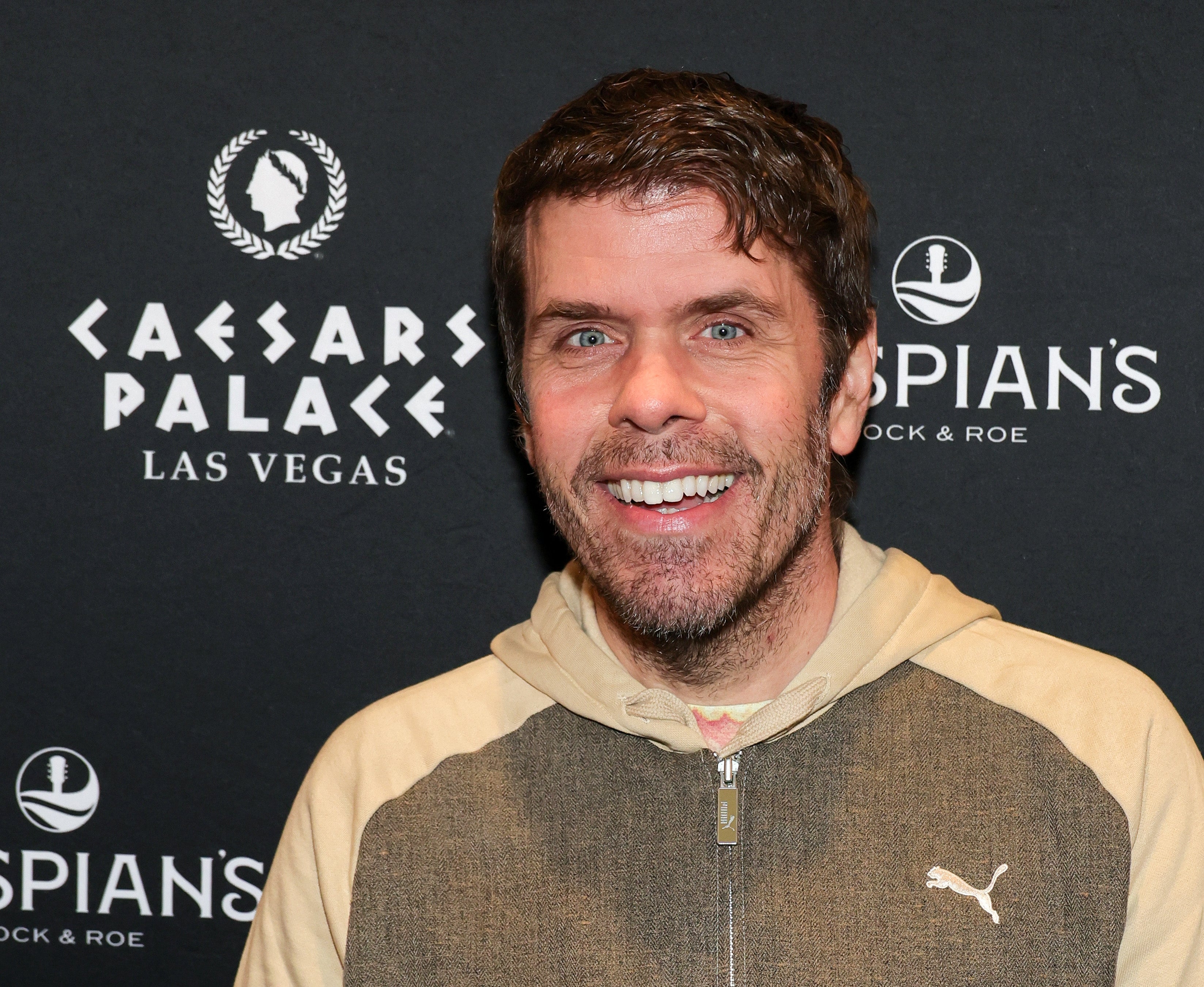 Person at a Caesars Palace event, wearing a casual hooded jacket with a Puma logo, smiling at the camera