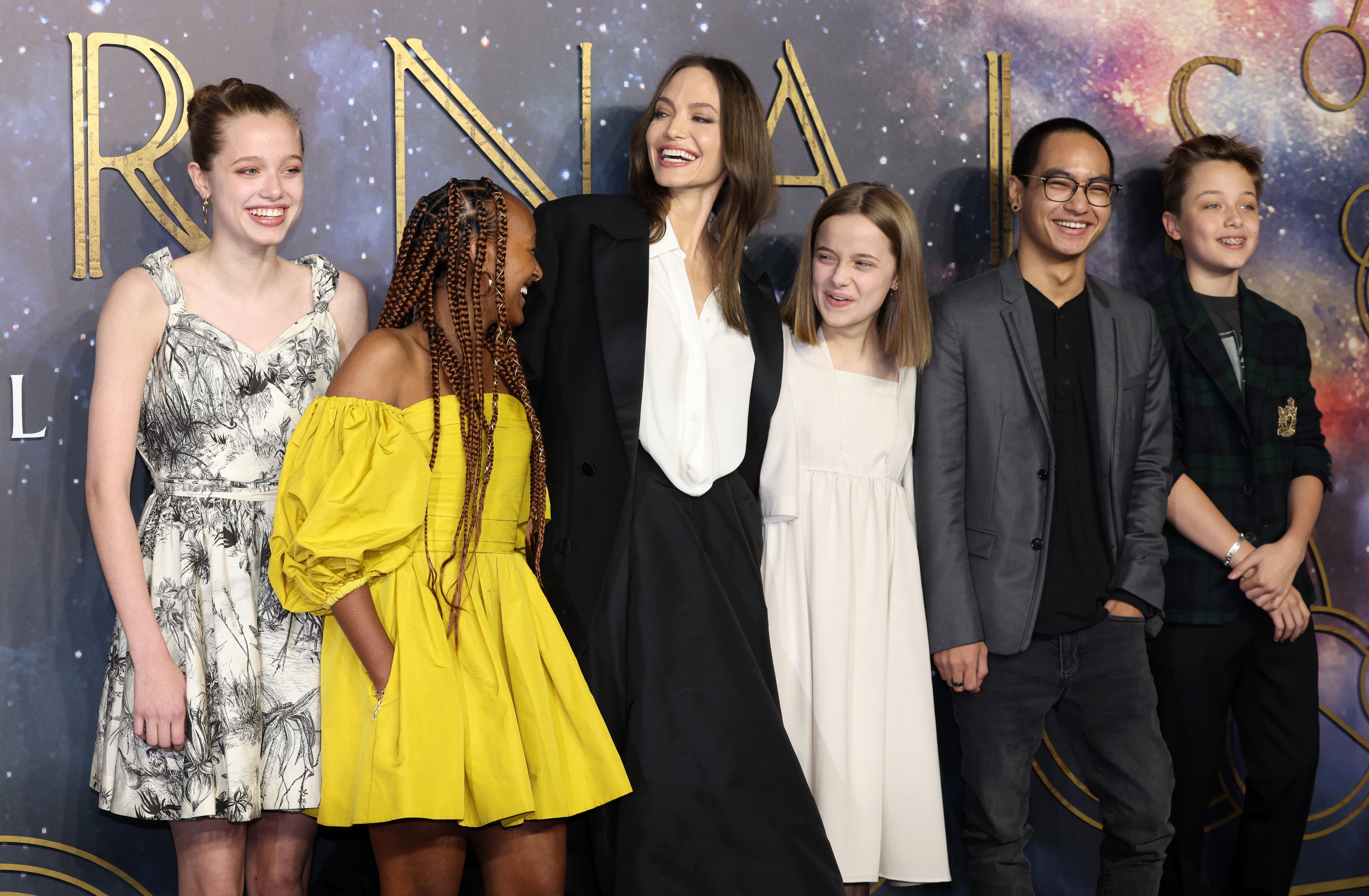 A group of people, including one in a long black coat, pose together at an event