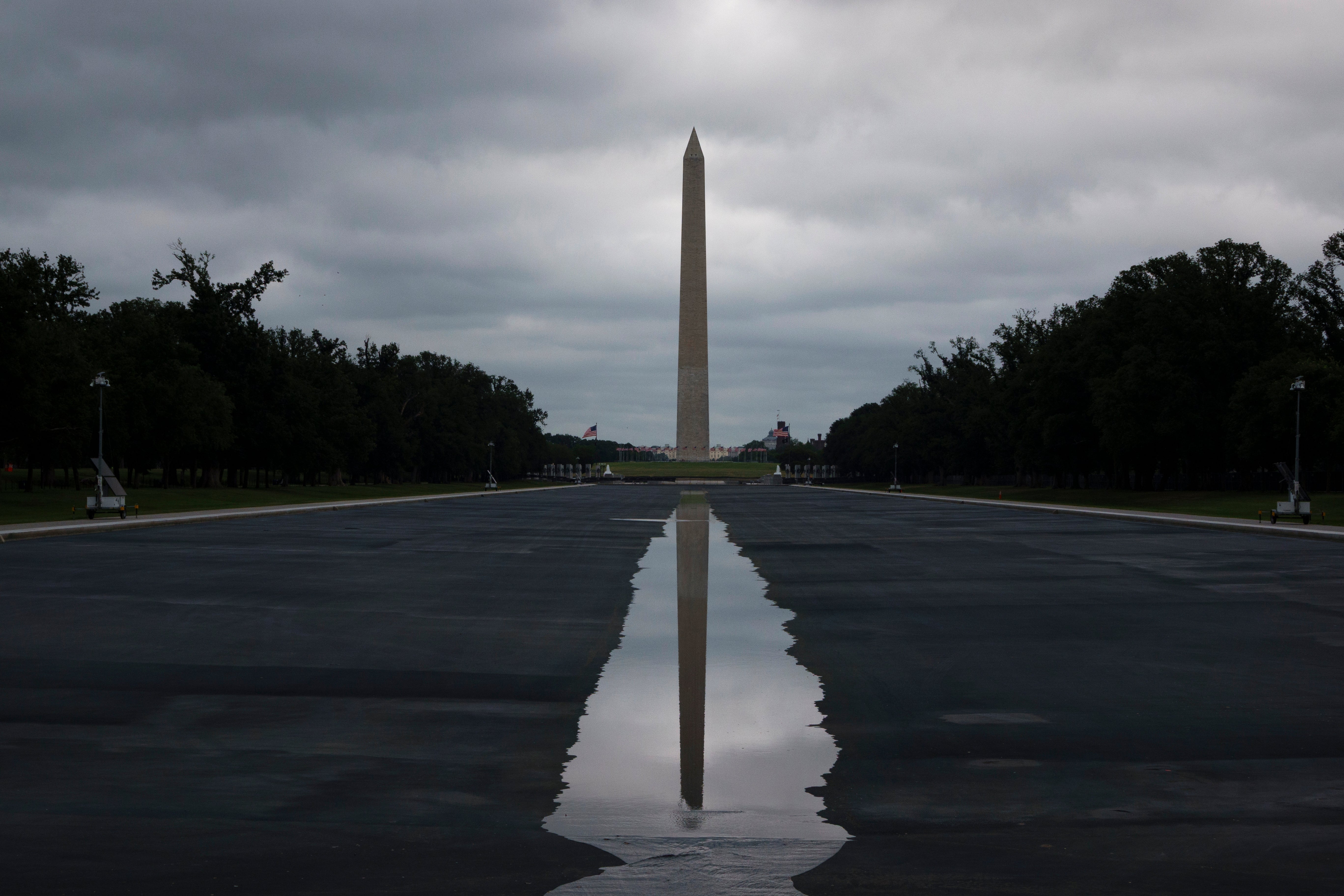 Refleksjon av Washington-monumentet i en sølepytt på National Mall, med overskyet himmel