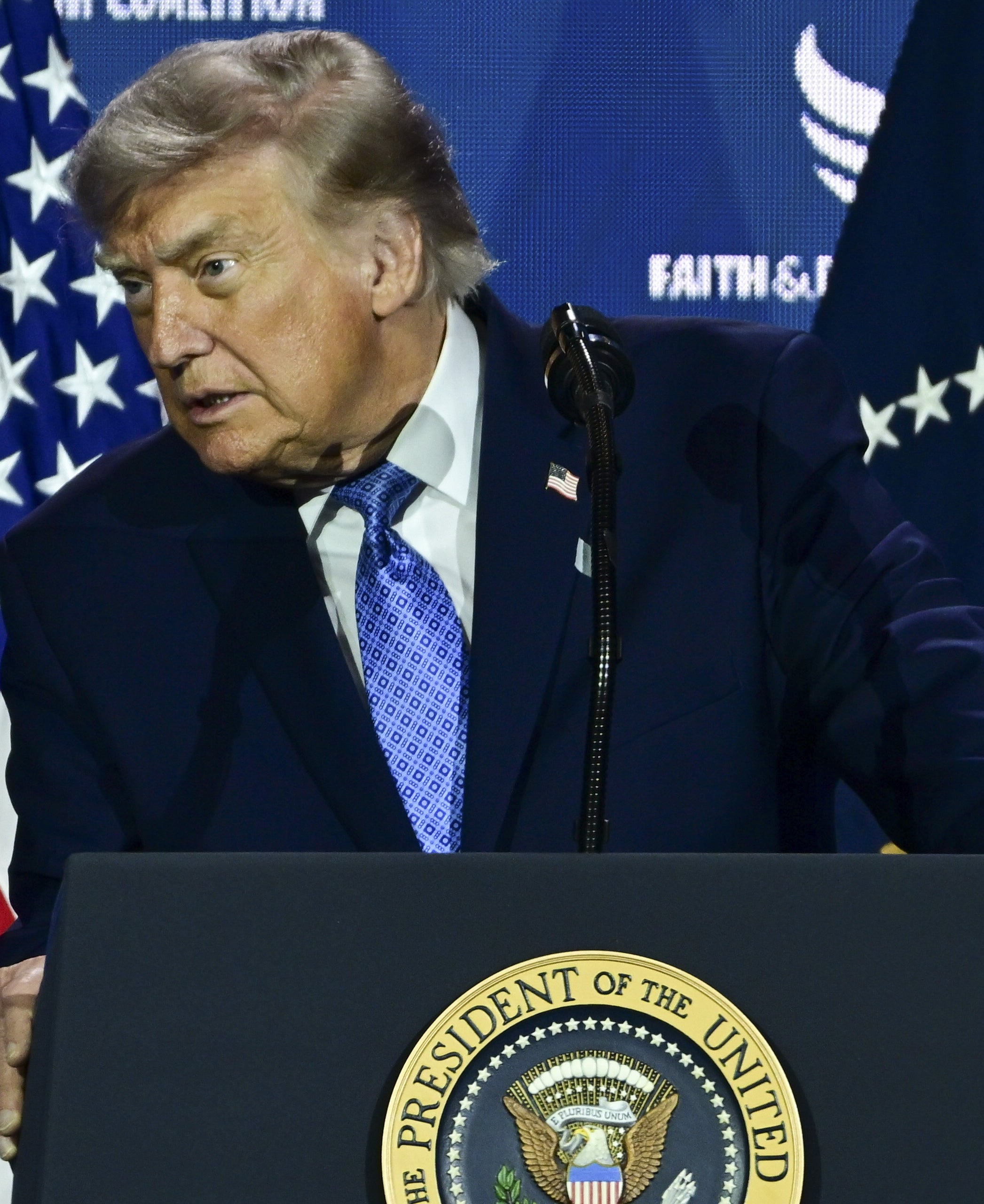 Mann på et podium med et segl der det står «President of the United States»," Amerikanske flagg i bakgrunnen