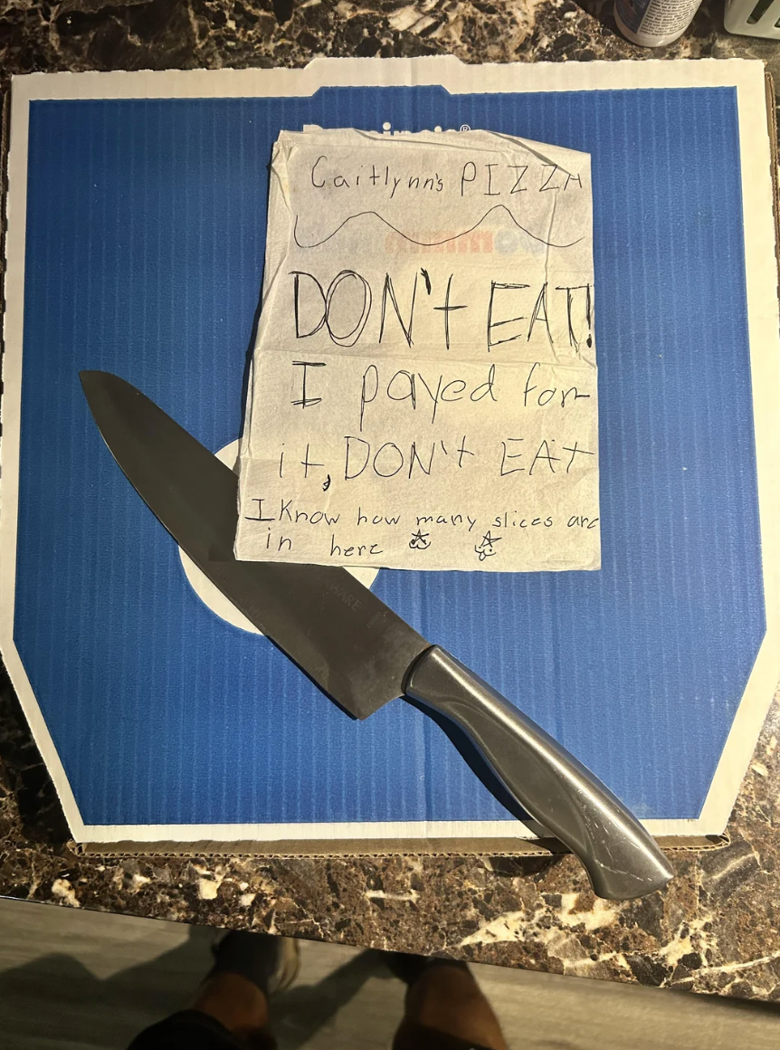 A closed pizza box with a handwritten note saying, "Caitlynn's PIZZA. DON’T EAT! I payed for it, DON’T EAT. I know how many slices are in here." A knife is on top