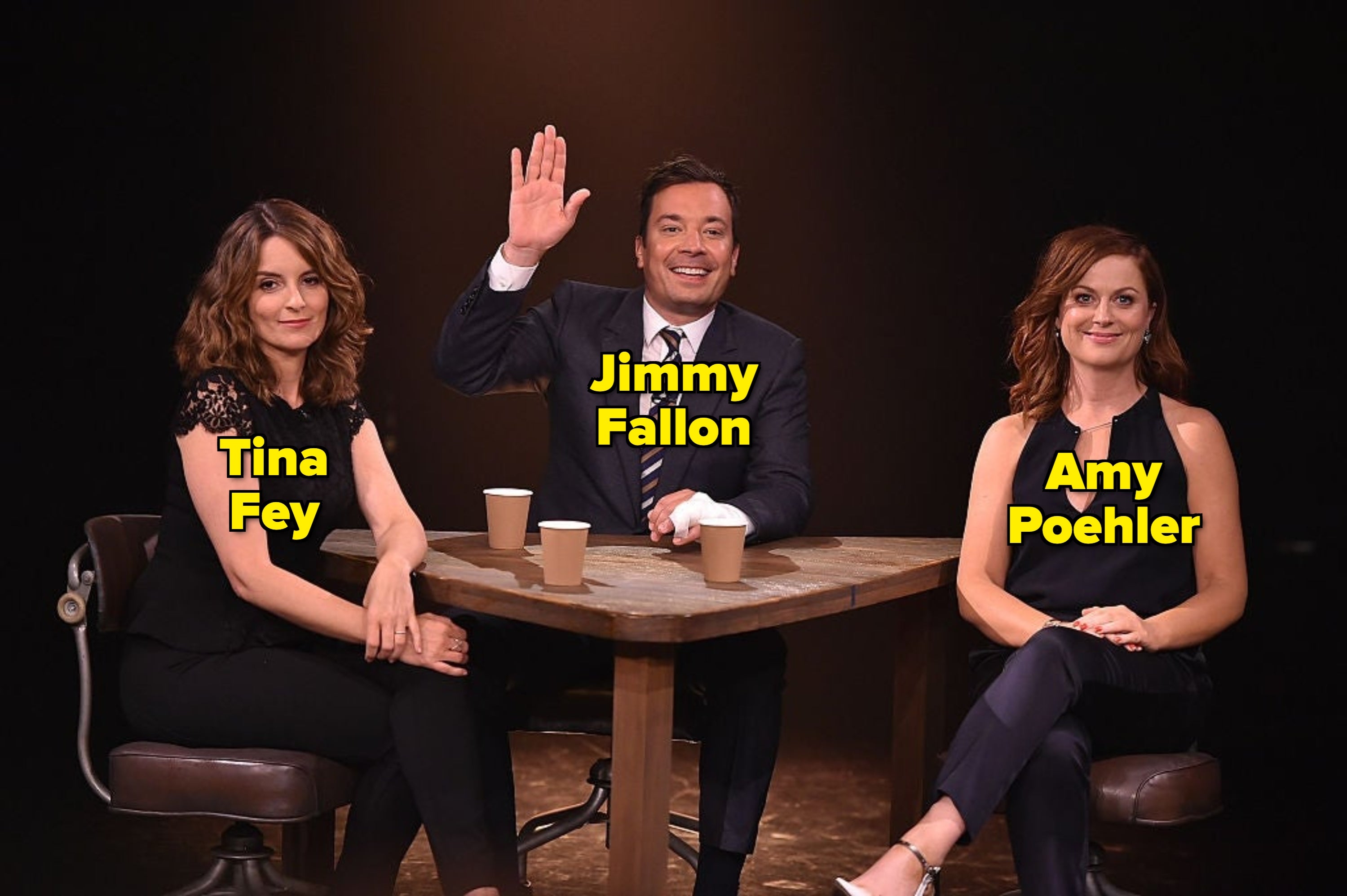 Tina Fey, Jimmy Fallon, and Amy Poehler sitting at a table with coffee cups, smiling
