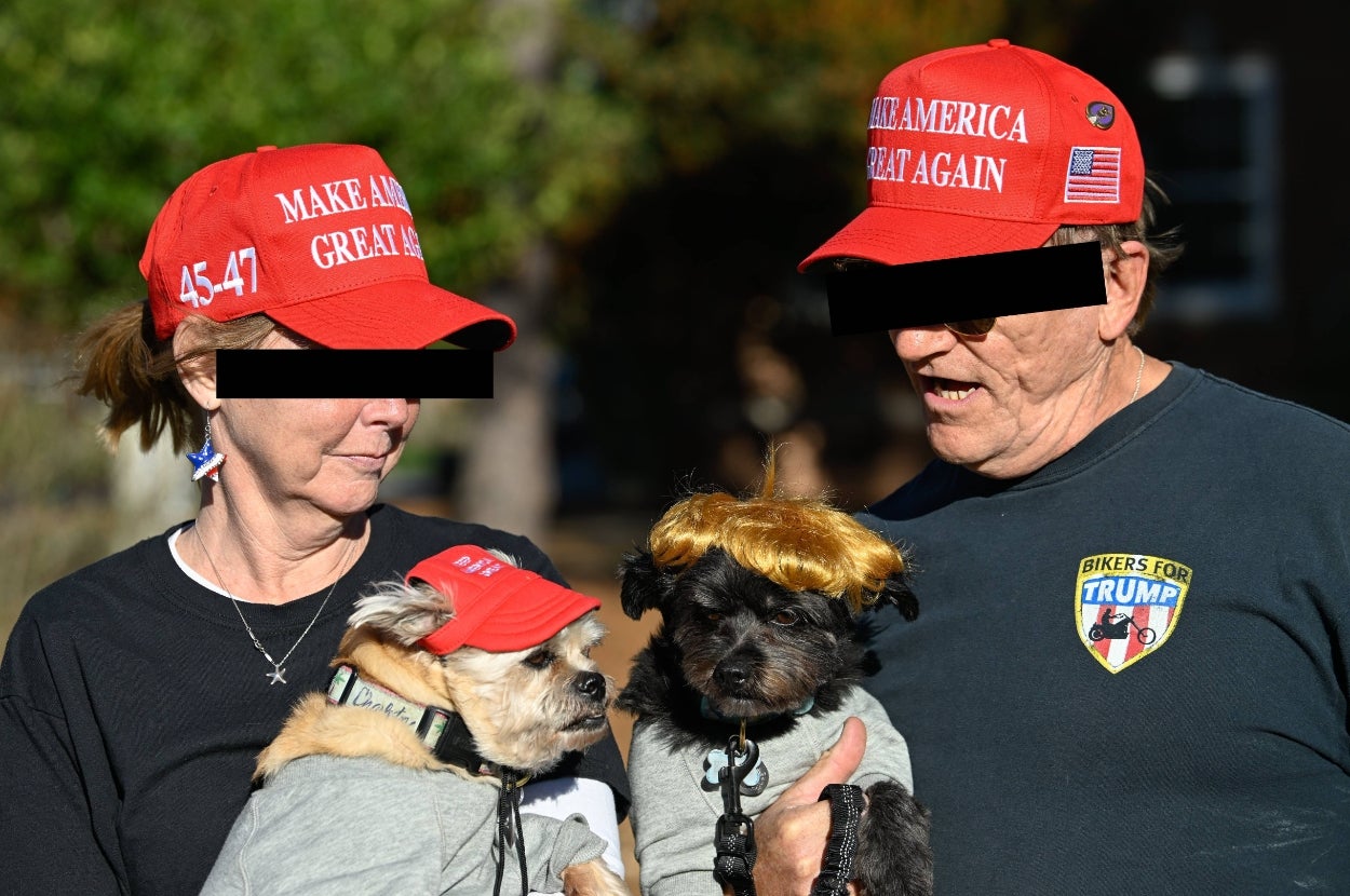 Two people and two dogs wear matching "Make America Great Again" hats; one dog sports a wig