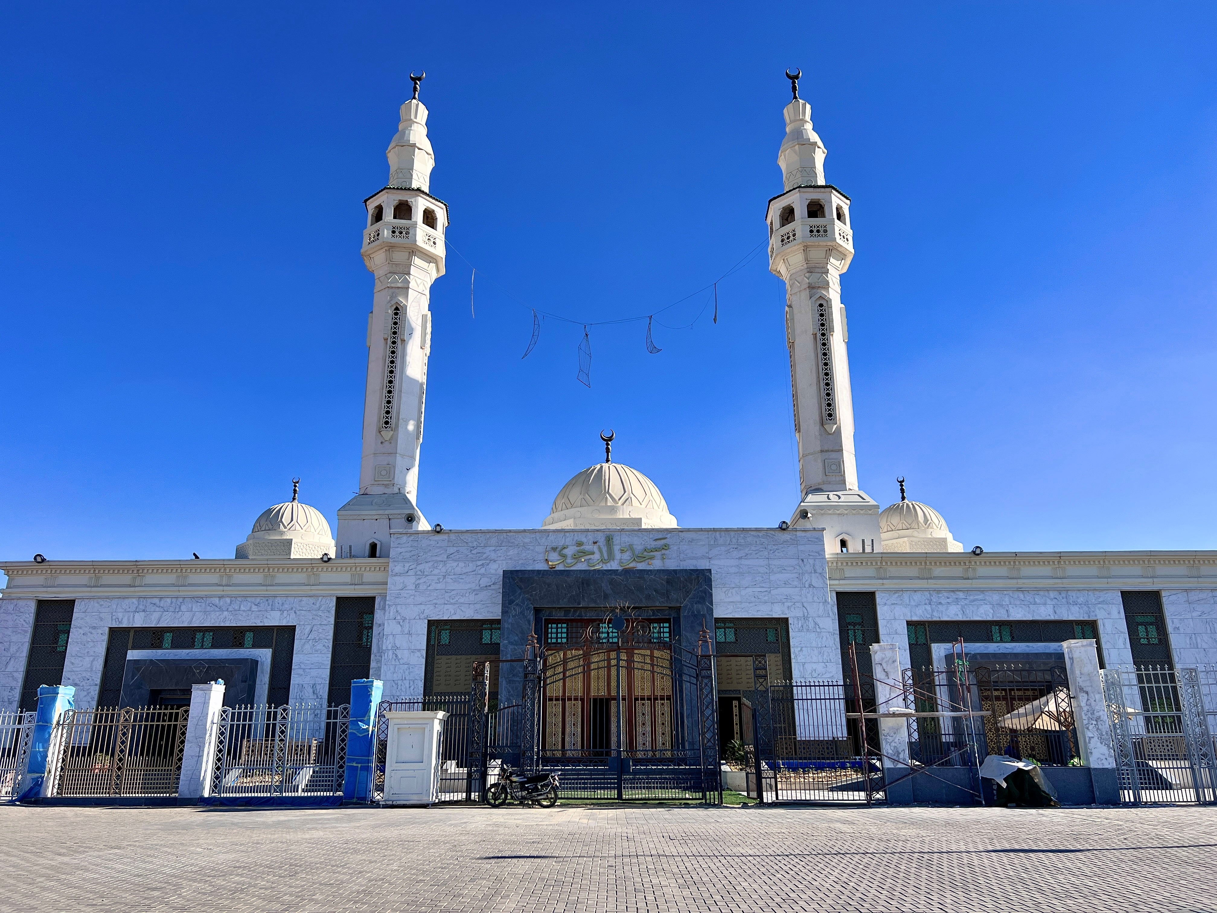 En stor moske med to høye minareter og en sentral kuppel, med intrikate arkitektoniske detaljer