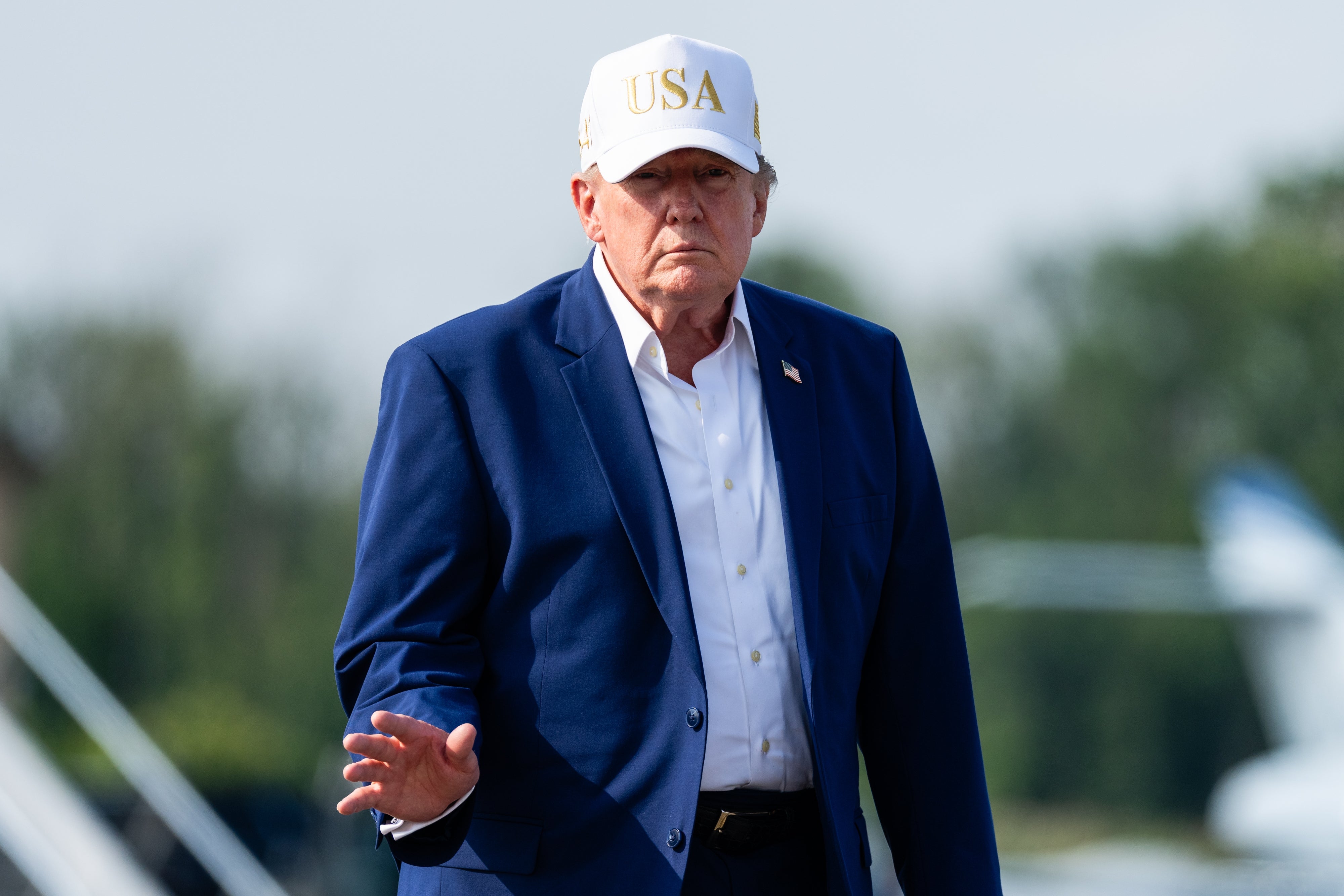 En person i blå dress og USA-caps-bevegelser mens han er utendørs i nærheten av et fly