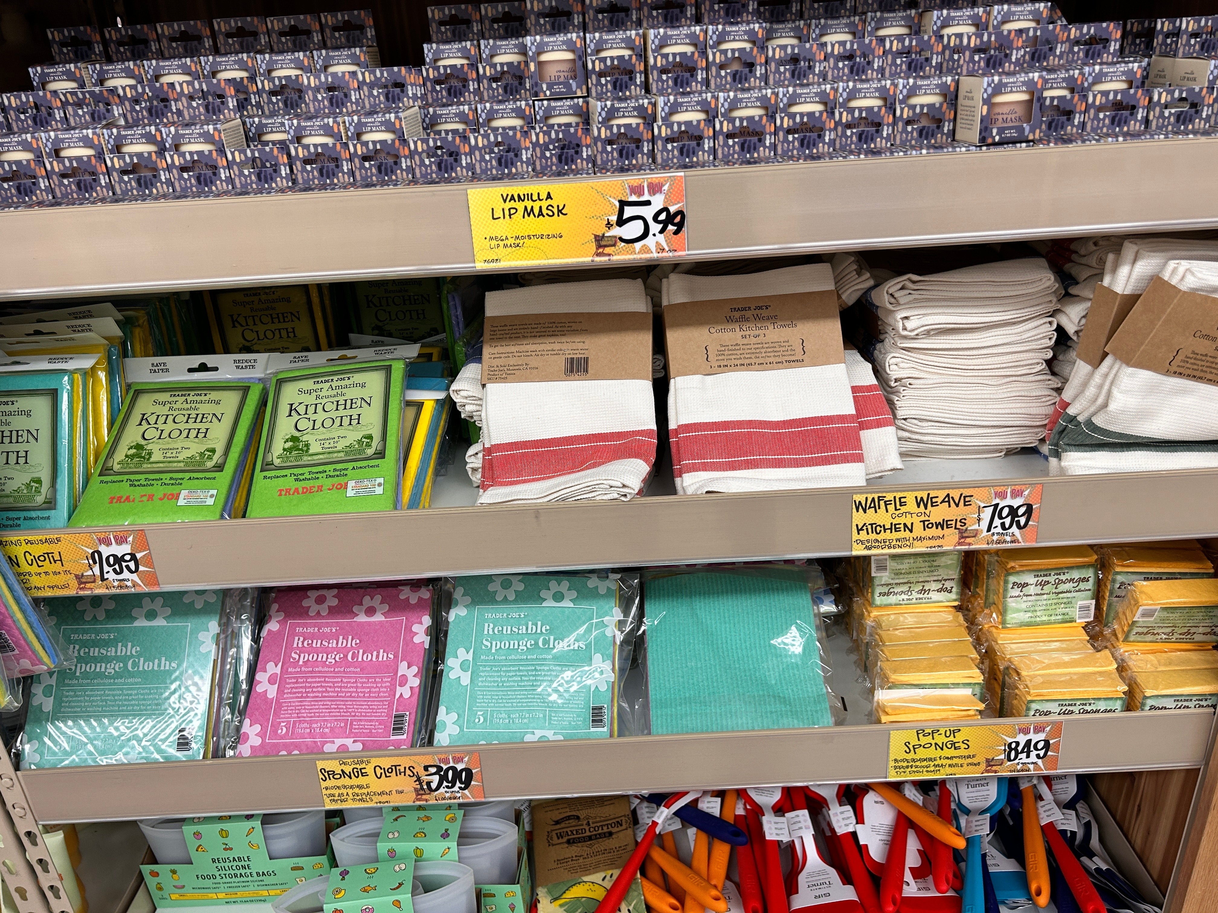 Store support displaying assorted cleaning supplies, reusable cloths, sponges, and packaged room towels with disposable terms tags