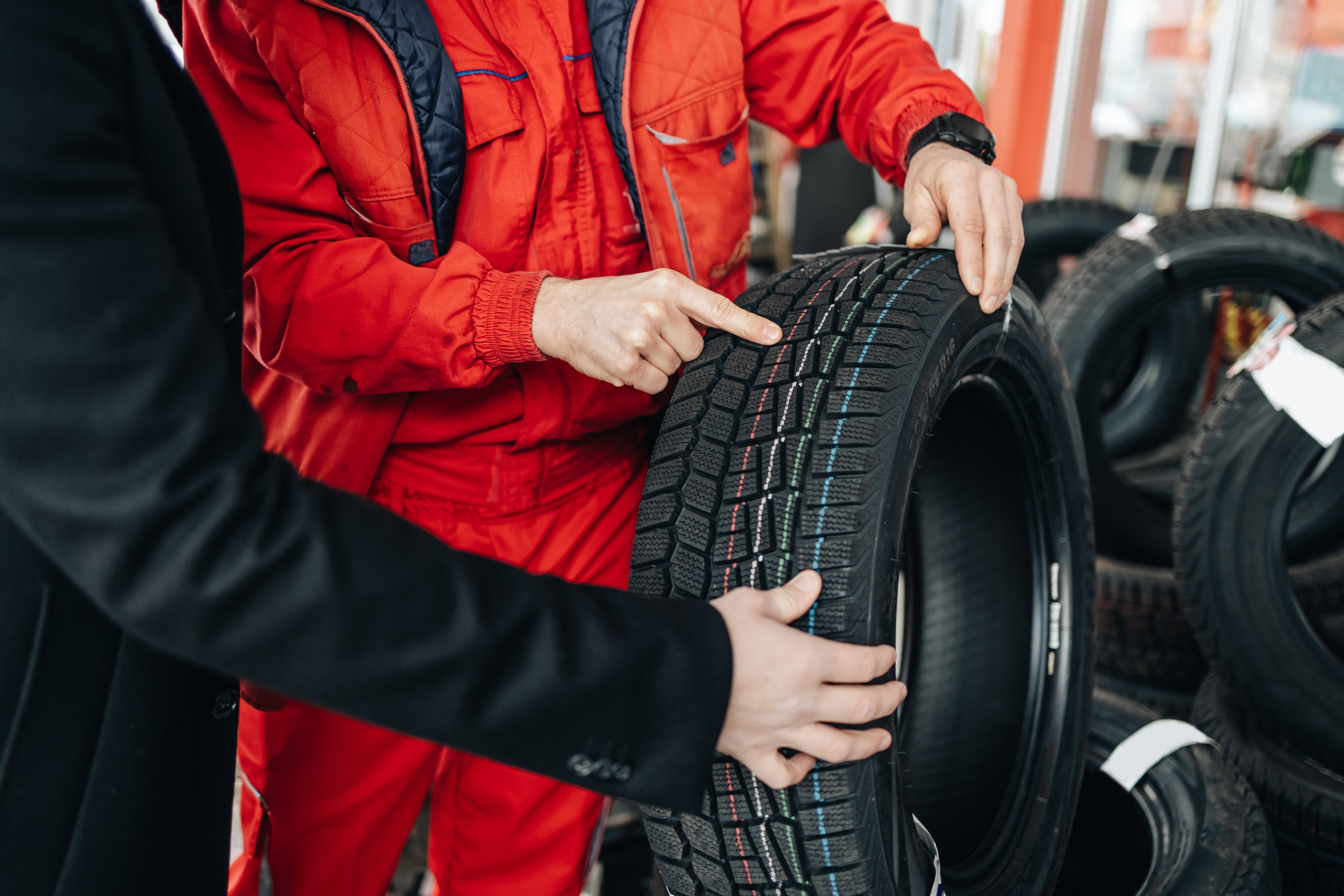 Two radical examining a car tyre successful a workshop; 1 points astatine the tread portion the different holds it