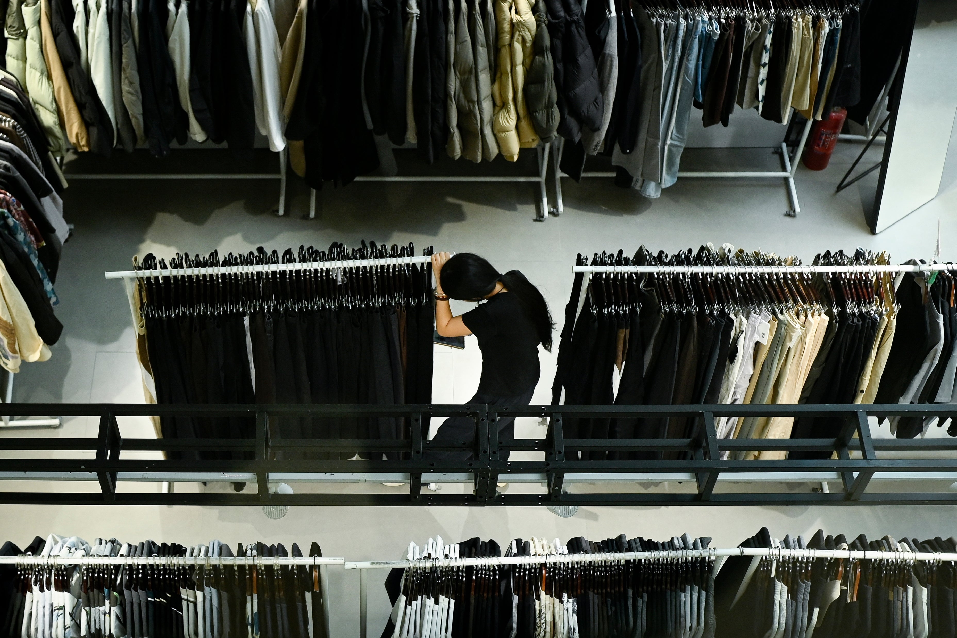 Person browsing covering racks successful a store, viewed from above