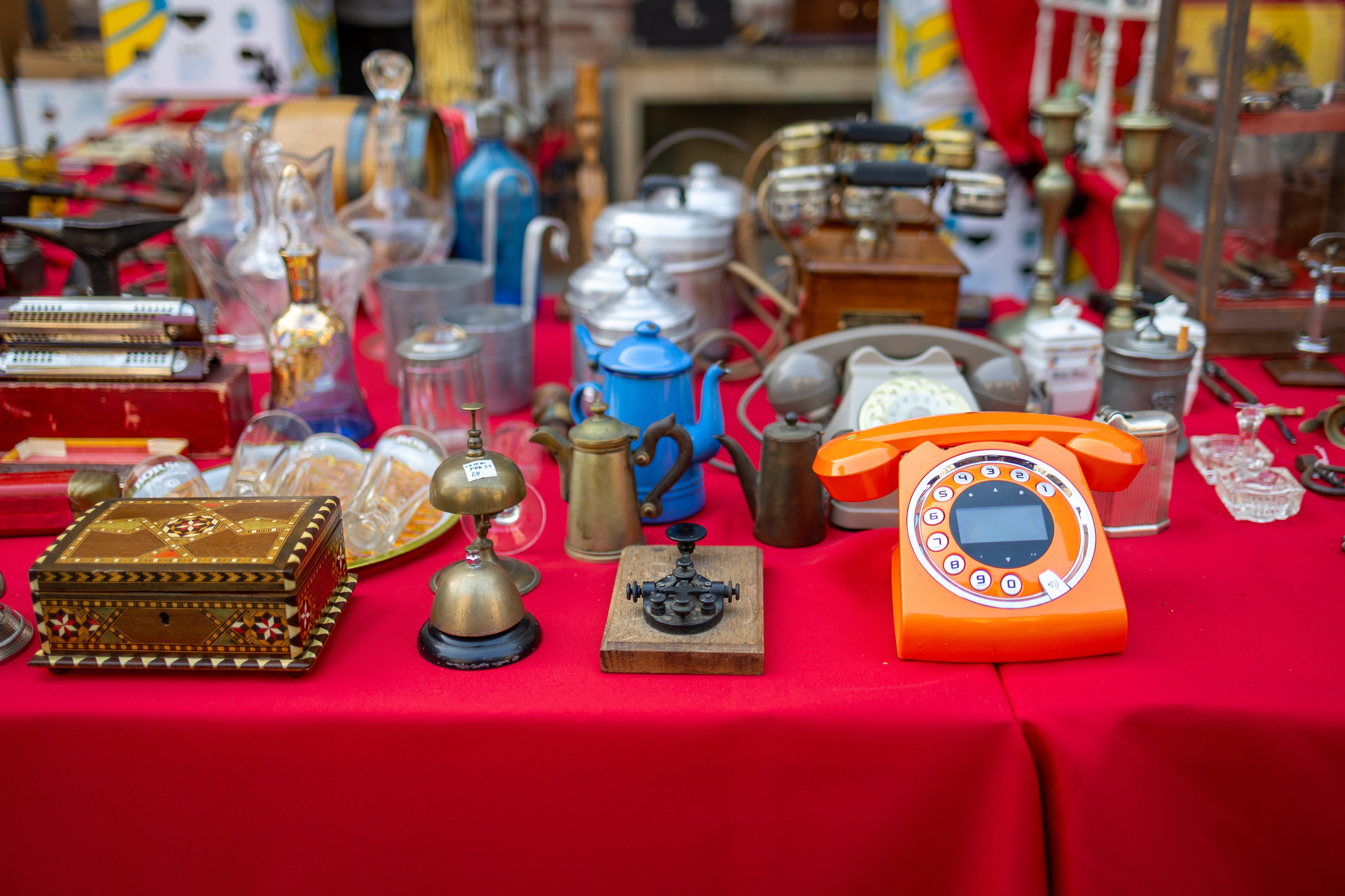 Various vintage items displayed connected a table, including an orangish rotary phone, teapots, lanterns, and glassware