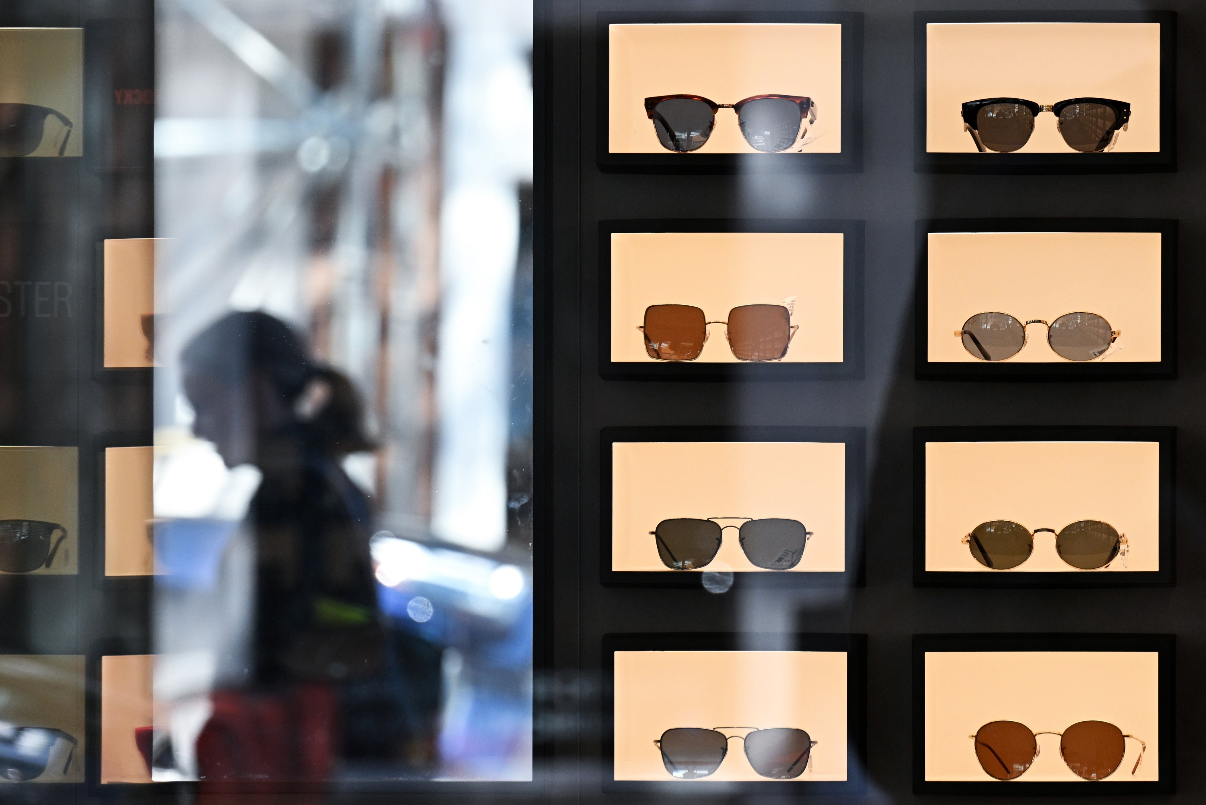 Display of assorted sunglasses successful a store model with a blurred reflection of a idiosyncratic outside