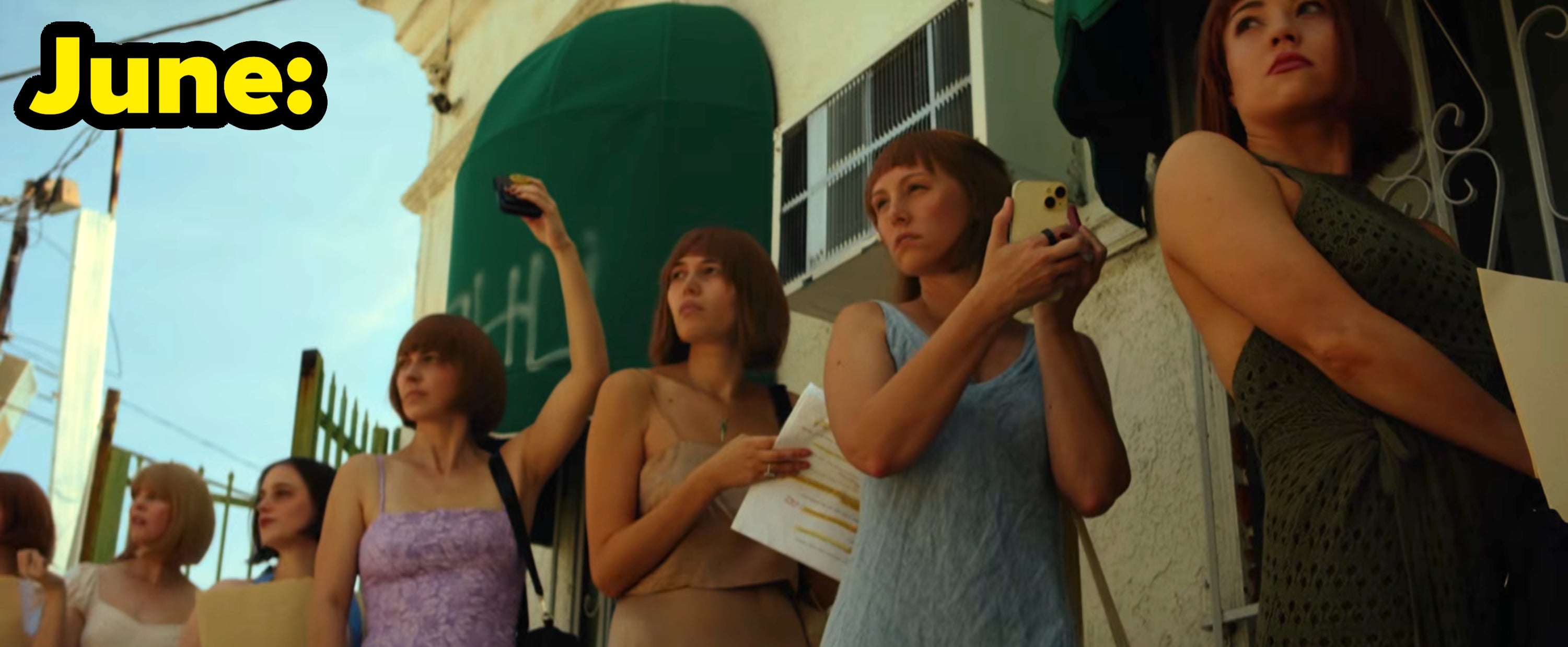 June's video, where a group of women holding phones and papers stand outside in a line