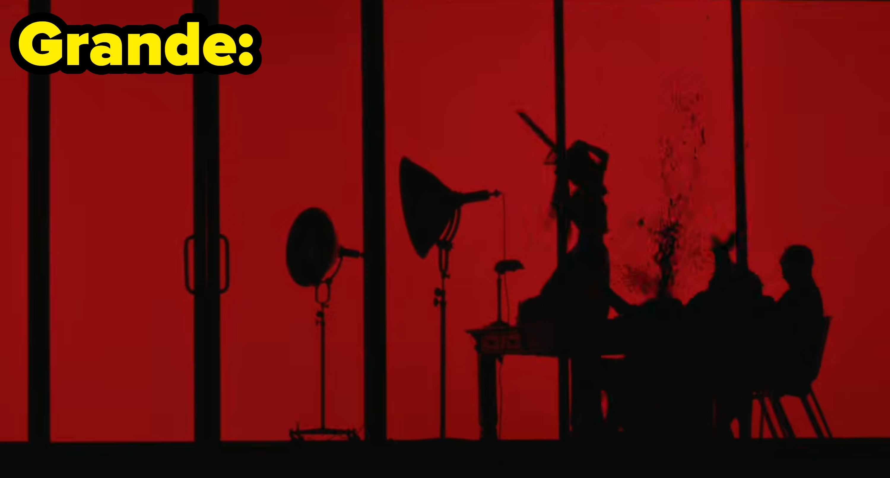 A silhouette of Grande wields a chainsaw as she kills the male executives
