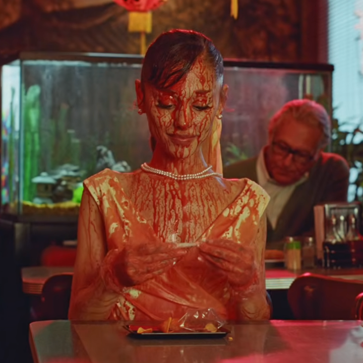 Grande smiling to herself in a diner as she is covered in blood