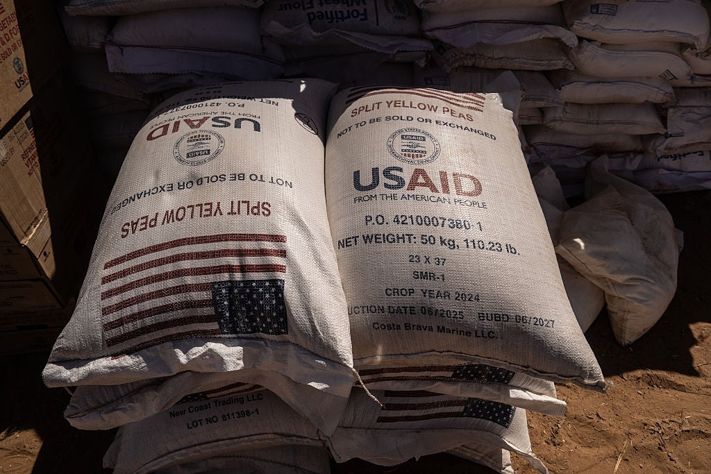 Poser med delte gule erter med USAID-logoer, som indikerer matvarehjelp beregnet på utveksling, stablet i et lagringsområde