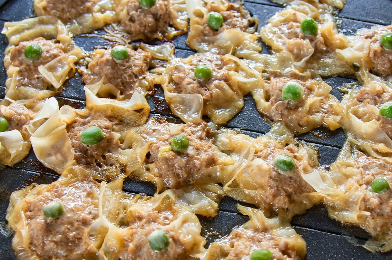 鉄板で焼かれたシュウマイが並んでいる。各シュウマイの上にはグリンピースがのっている。