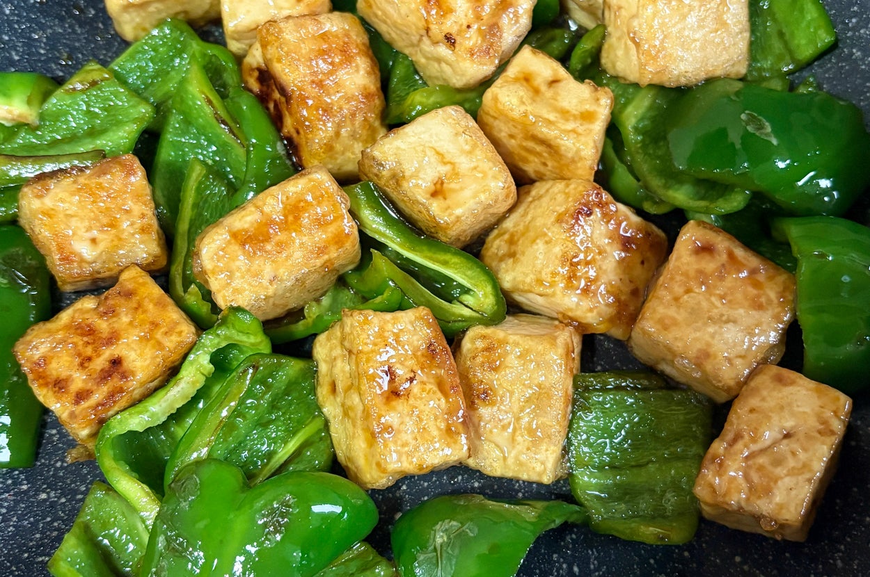焼き豆腐とピーマンがフライパンで炒められている料理。