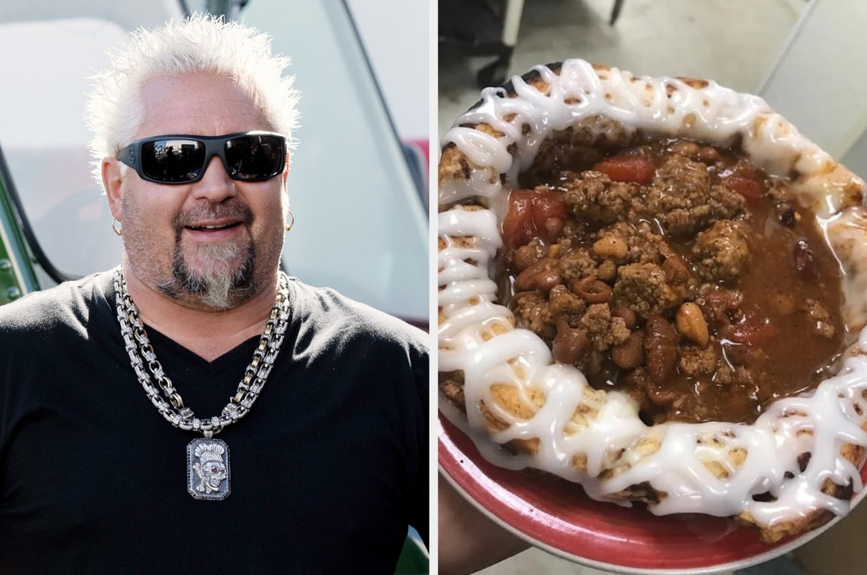 A person with spiked hair and sunglasses smiles next to a dish of chili topped served in an edible cinnamon bun bowl