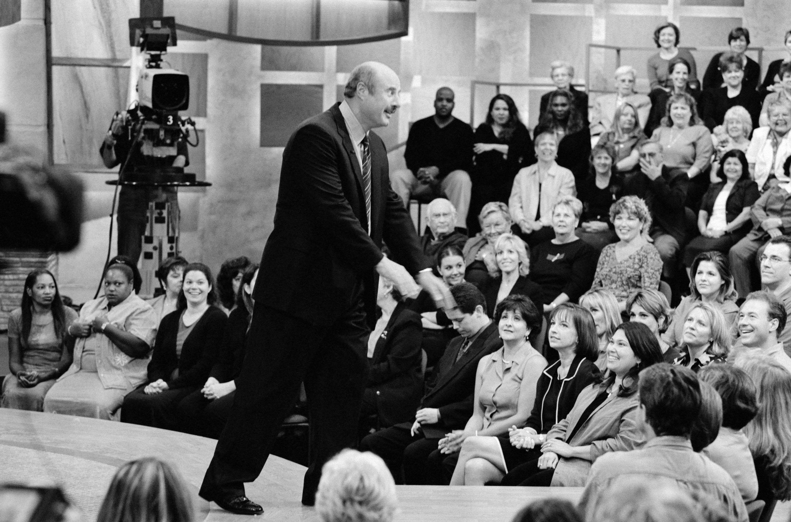 En talkshowvert engasjerer seg med et live studiopublikum, som sitter i lagdelte rader, under en filmøkt