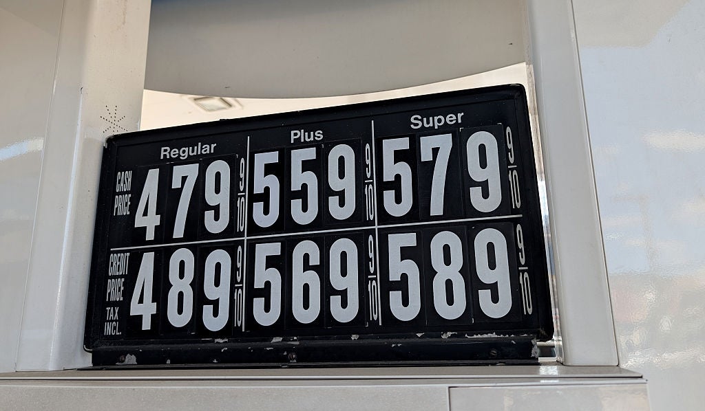 Gas prices displayed on a sign: Regular $4.79, Plus $5.59, Super $5.79. Prices with tax: Regular $4.89, Plus $5.69, Super $5.89