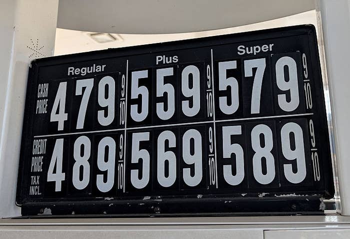 Gas prices displayed on a sign: Regular $4.79, Plus $5.59, Super $5.79. Prices with tax: Regular $4.89, Plus $5.69, Super $5.89