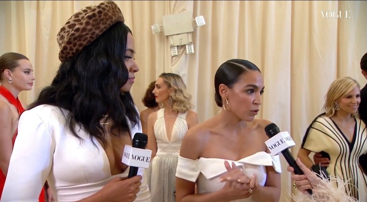 Alexandria Ocasio-Cortez stands beside her stylist Aurora James as she talks to Vogue Magazine about her Met Gala look.