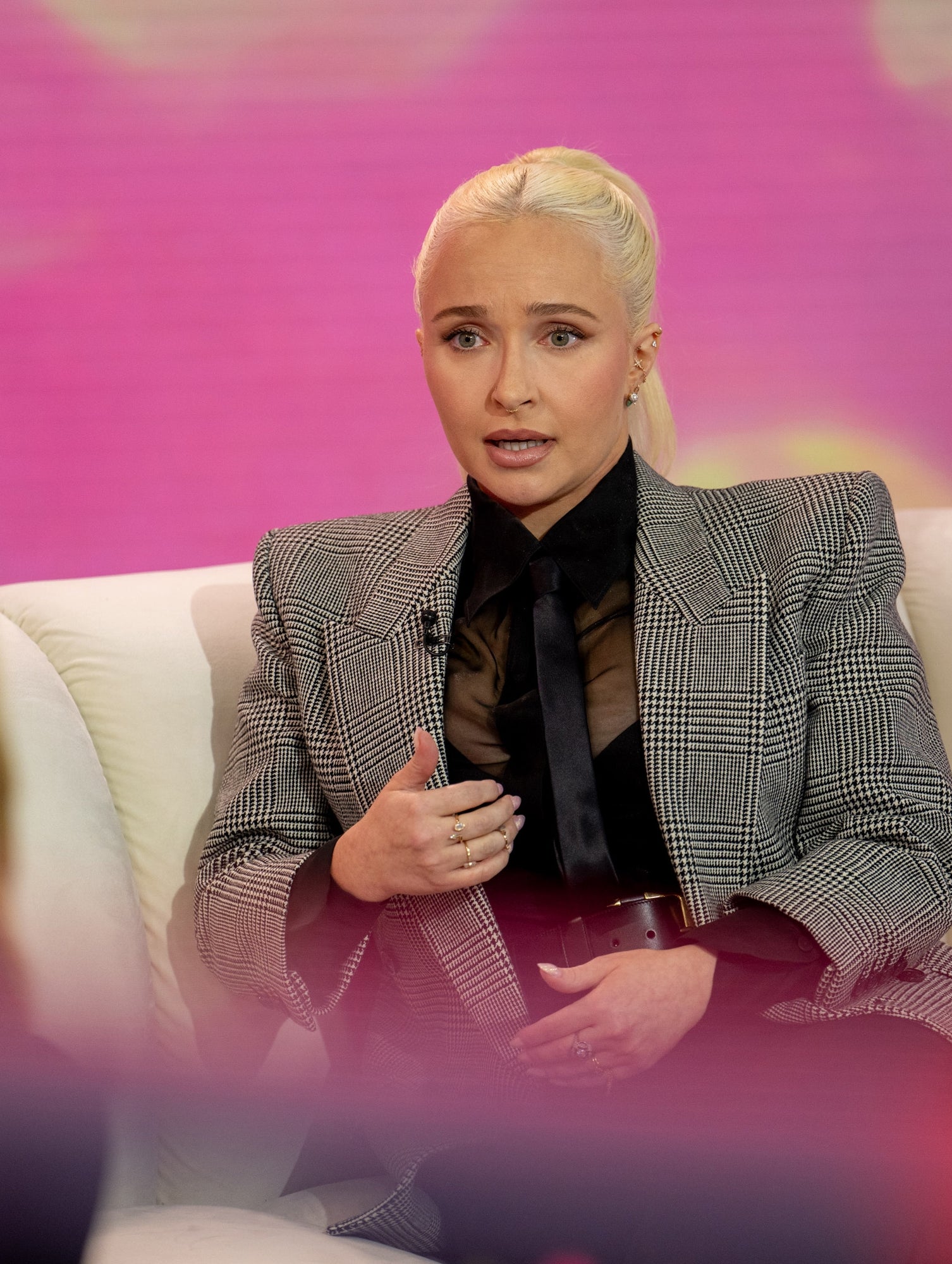 Hayden seated on a sofa in a TV studio setting