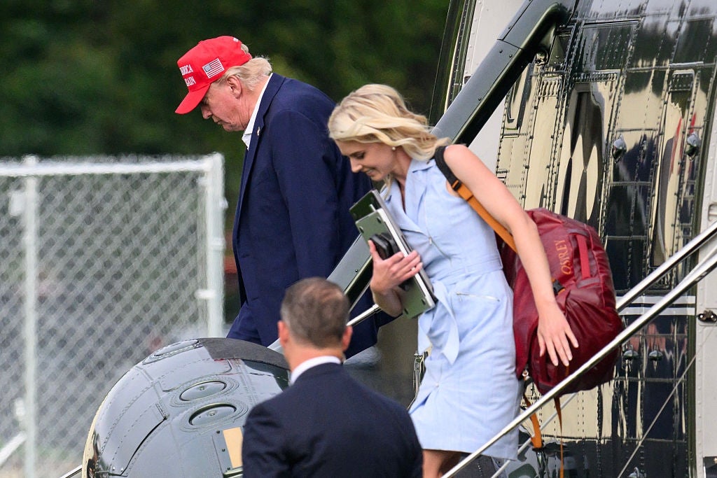 To personer går ned trappetrinnene til et fly. Den ene har på seg dress og rød caps, den andre holder et nettbrett og har en ryggsekk, kledd i et lett antrekk