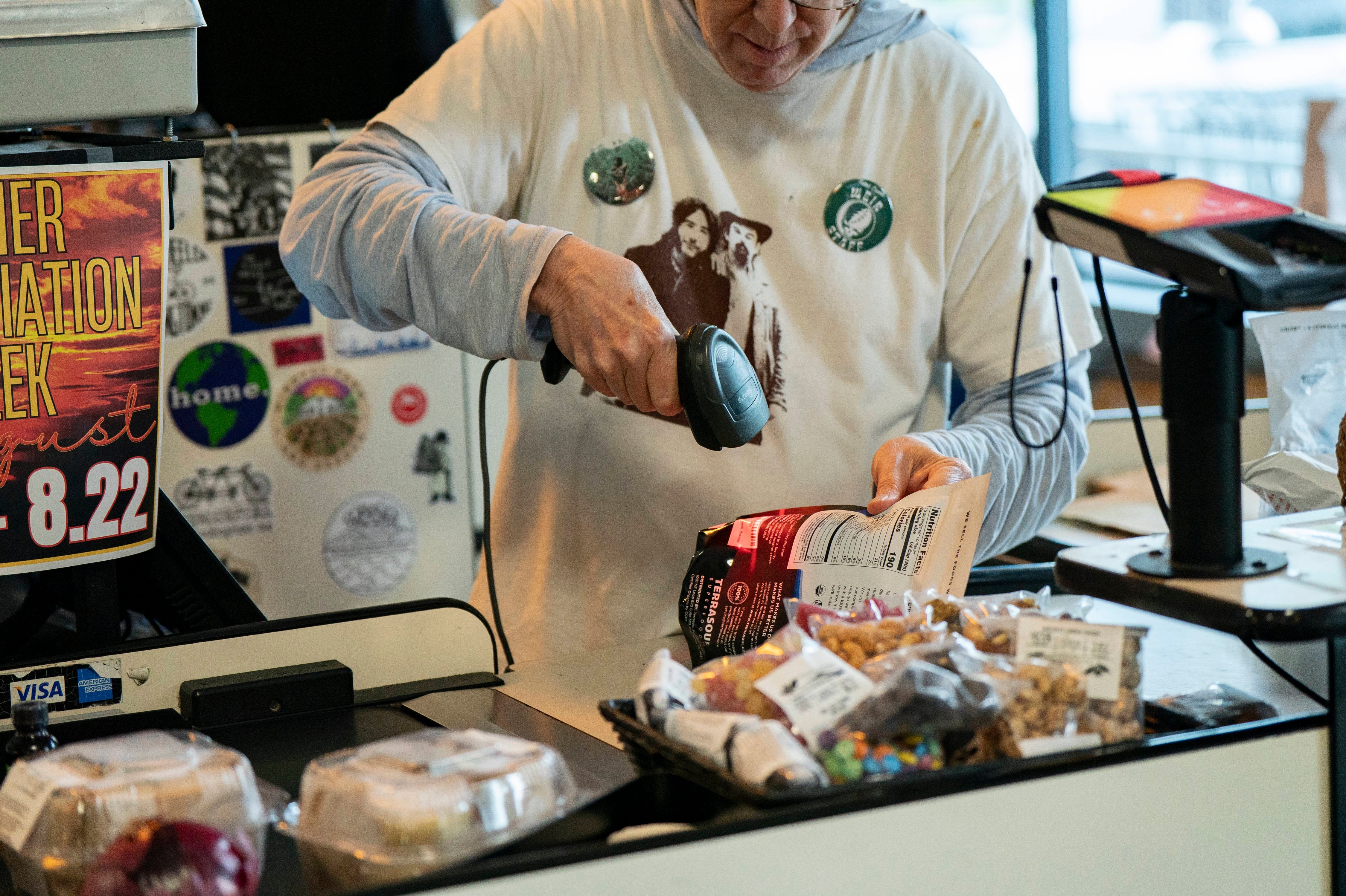 Person ved en butikk som skanner dagligvarer, inkludert en pose chips og pakket matvarer