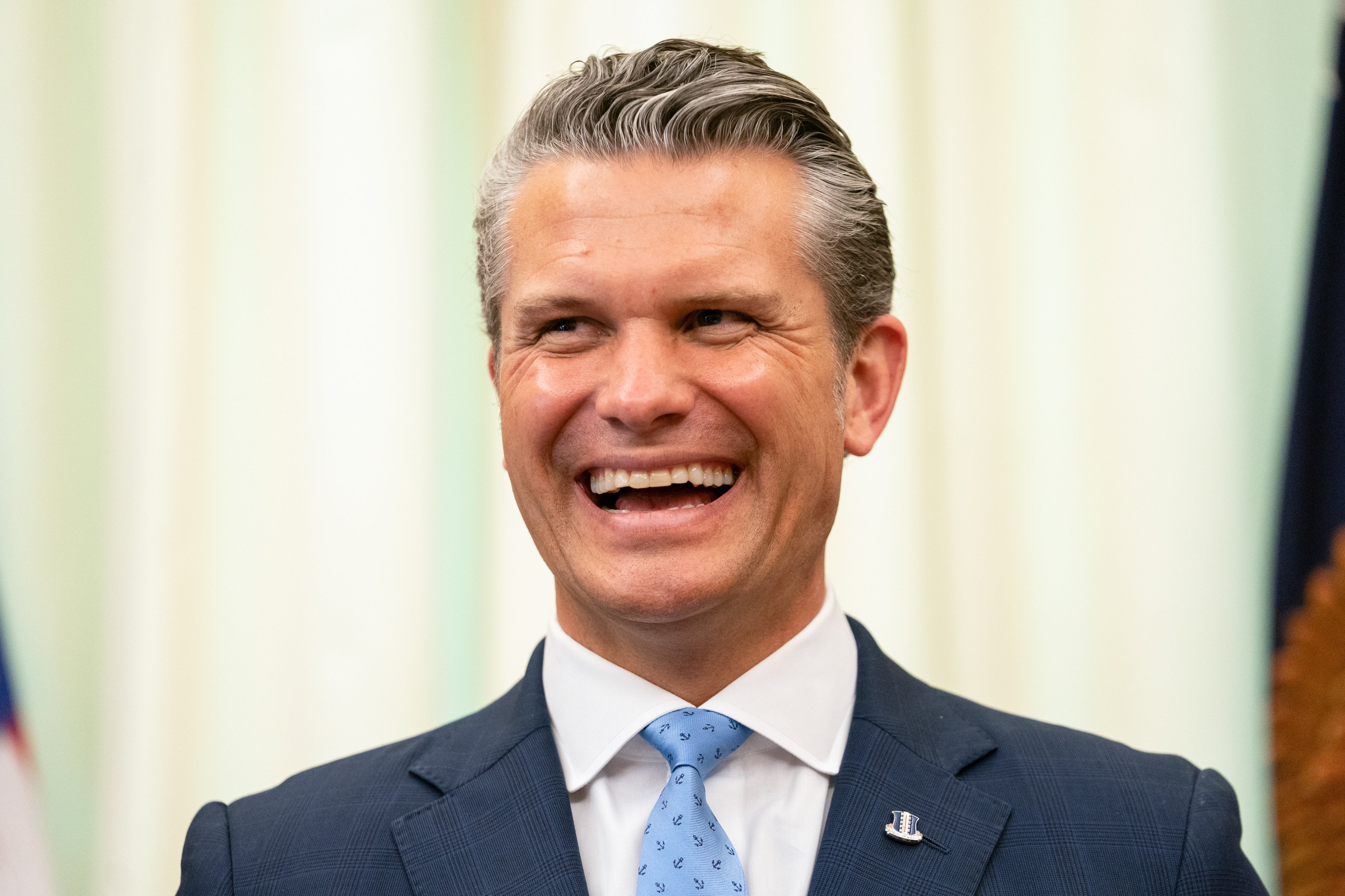 Smilende mann i dress og slips med jakkeslagsnål, stående innendørs