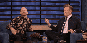 Aaron Paul on the Conan O'Brien show, smiling and bowing to the audience.
