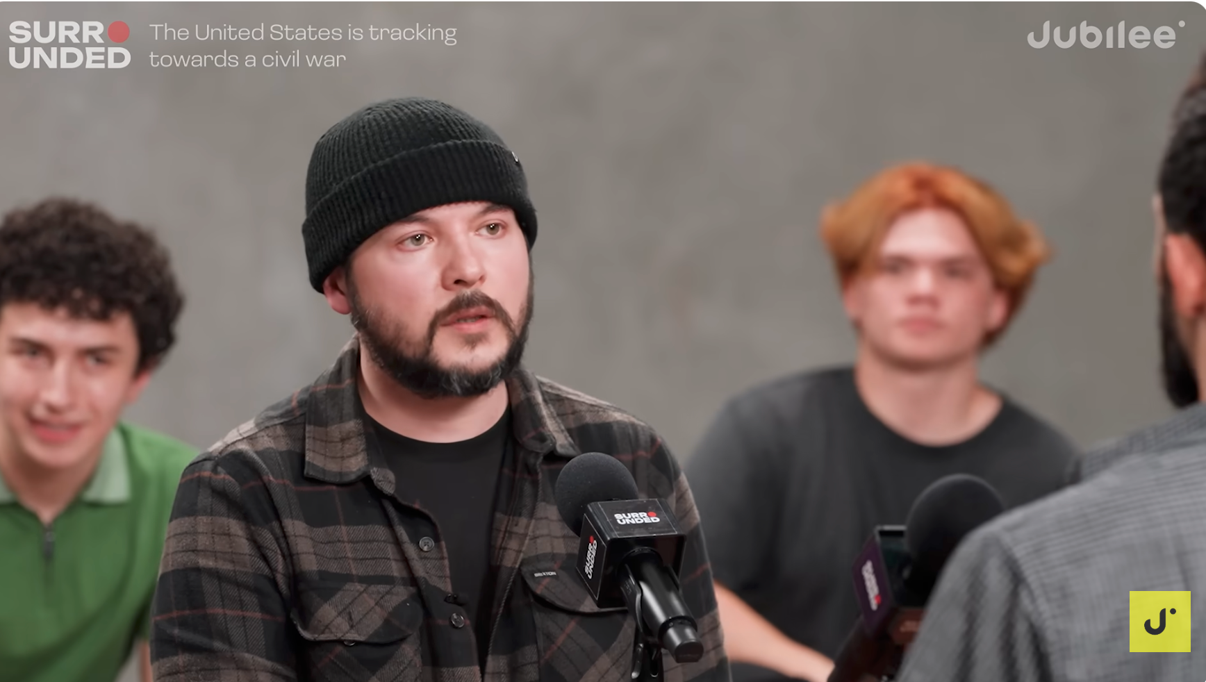 Tre personer i en seriøs diskusjon i et panel. En mann i en lue snakker og fokuserer på en usett person. Bannertekst leser om en borgerkrig