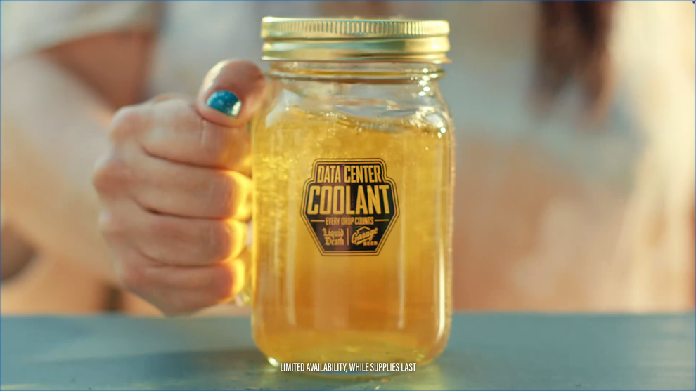 A hand holds a mason jar labeled "Data Center Coolant." The jar contains a golden liquid resembling a beverage