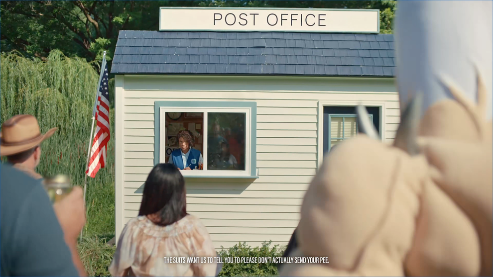 A person at a tiny post office window talks to visitors in outdoor setting. Text at bottom humorously advises against mailing physical samples