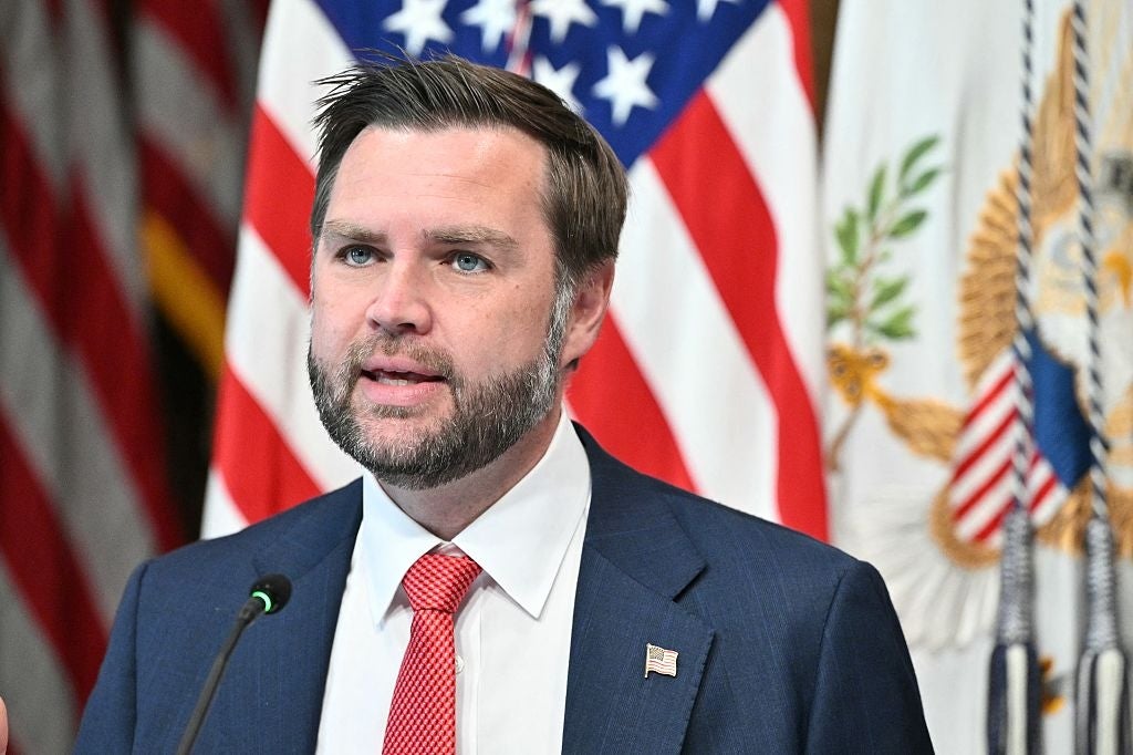 JD Vance i dress taler ved et podium, med amerikanske flagg i bakgrunnen