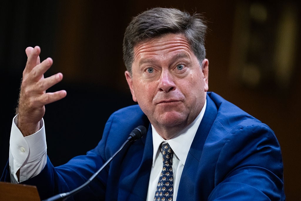 Jay Clayton, i dress, ser ut til å snakke på en konferanse eller høre, gestikulerer med en hånd og ser frem med løftede øyenbryn