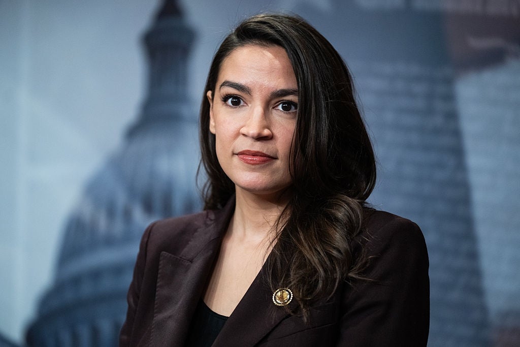 Alexandria Ocasio-Cortez i en formell blazer står foran et uskarpt bybilde som bakteppe