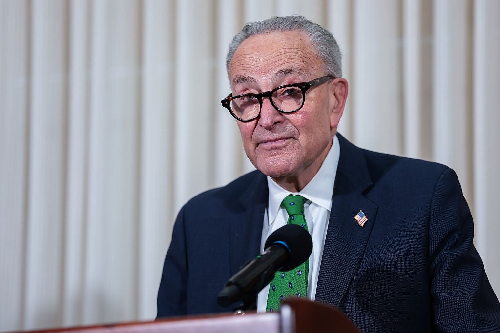 Chuck Schumer, i dress og slips, står ved et podium og taler