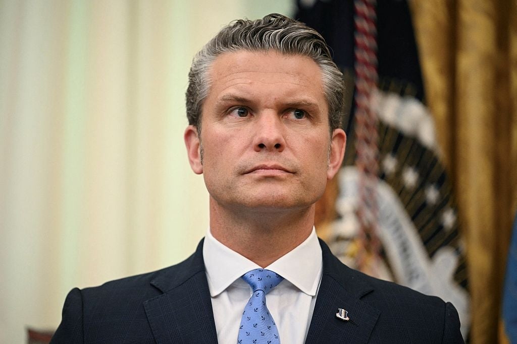 Pete Hegseth, i dress og slips, står i en formell setting