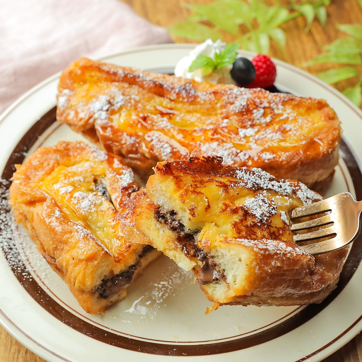 皿に盛られたフレンチトースト。フォークで一切れにカットされ、中にチョコレートが見える。上には粉砂糖がかけられている。