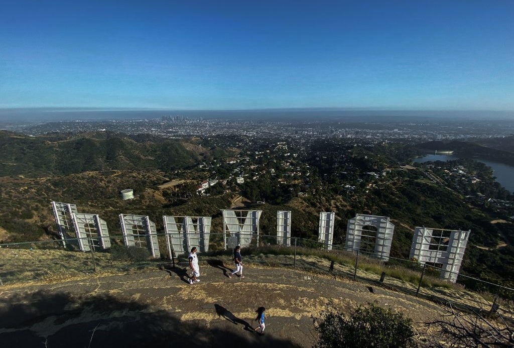 View from behind the Hollywood sign overlooking Los Angeles, with people walking along the trail in the foreground