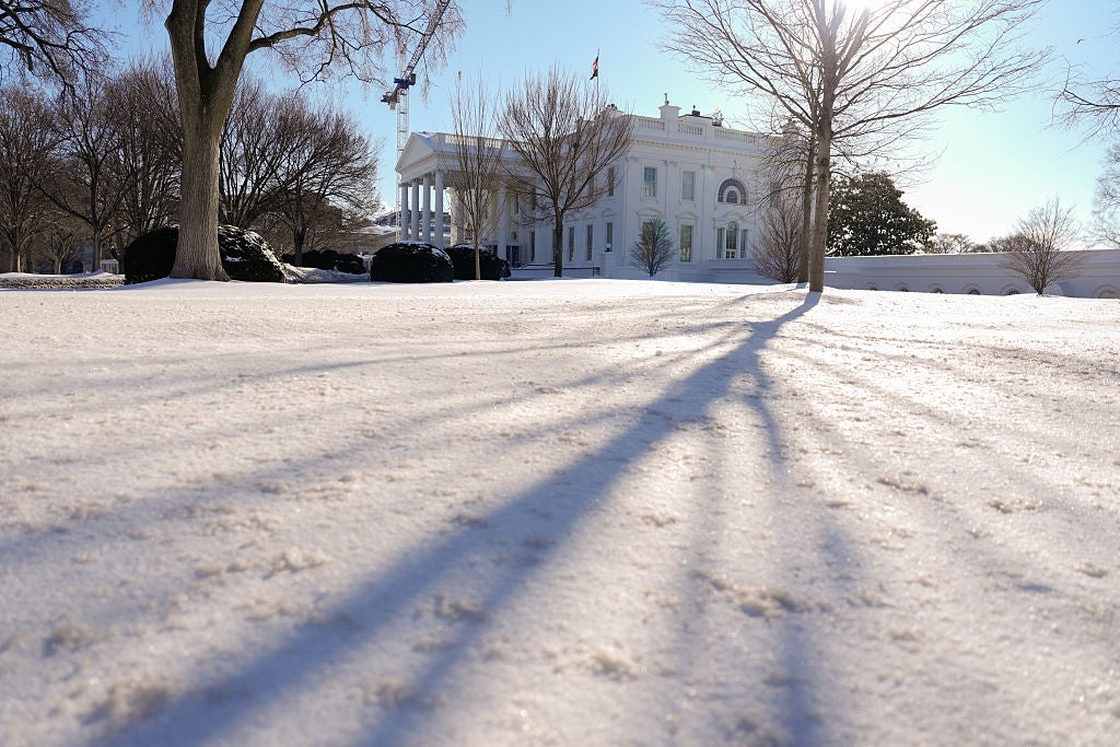 Snow-covered landscape in front of The White House, likely a governmental building, on a clear day