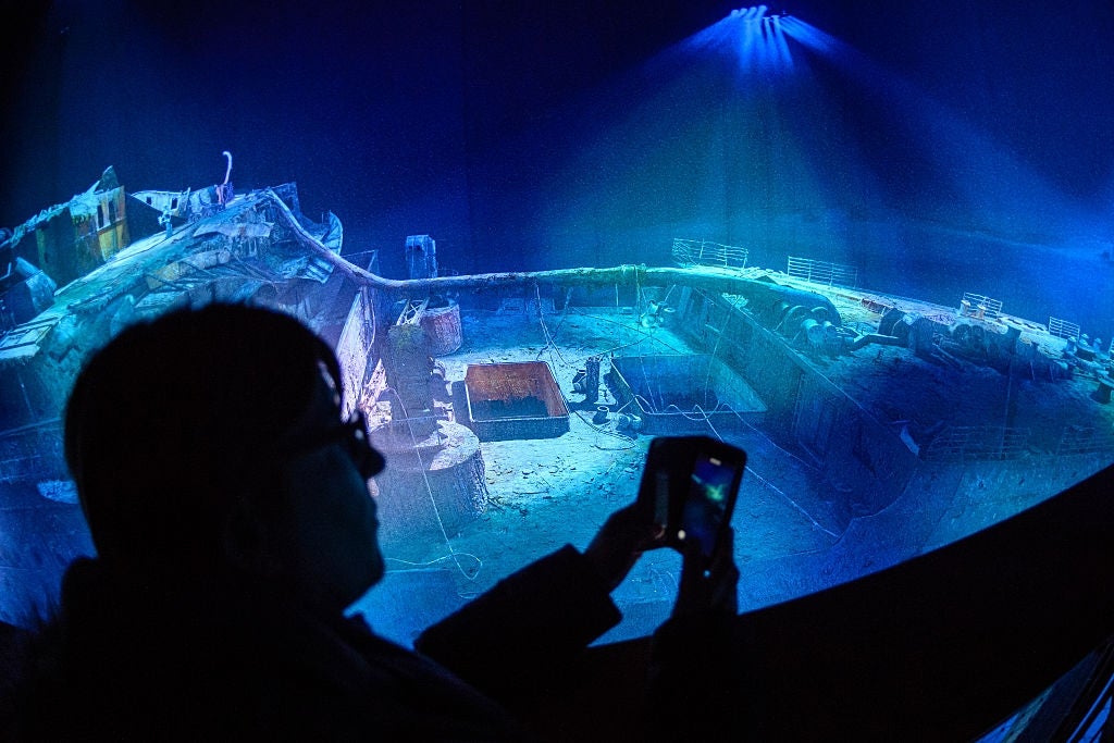 A woman takes a picture of a large-scale 360 degree panorama presentation of the Titanic shipwreck